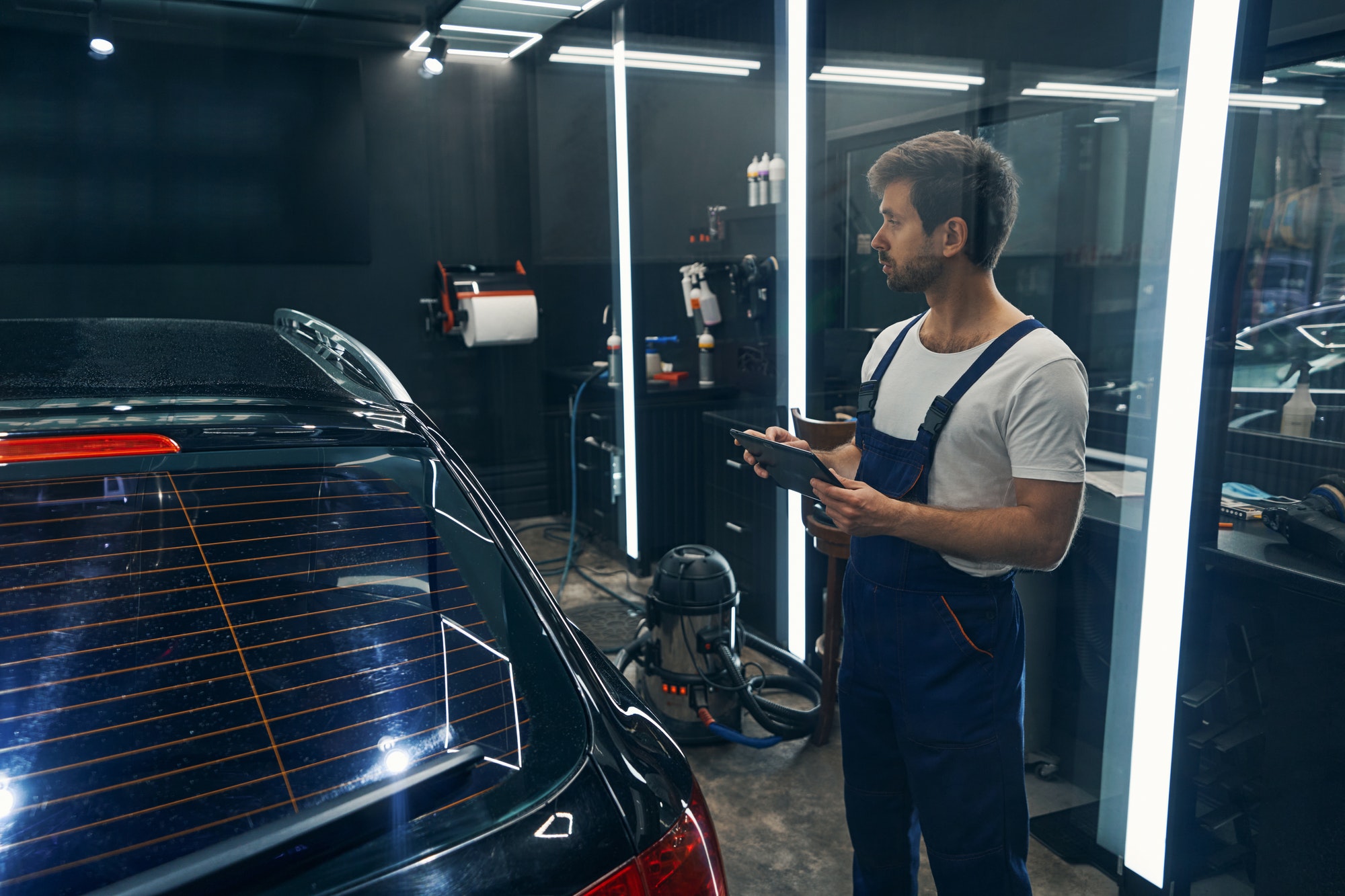 Worker of car service entering information about detailing to tablet